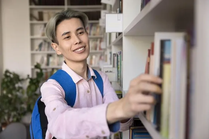 Framed Print : Happy Asian teen student guy choosing literature in university library Framed Print : Happy Asian teen student guy choosing literature in university library