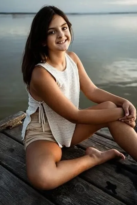 Framed Print : Happy girl sitting on jetty against lake Framed Print : Happy girl sitting on jetty against lake