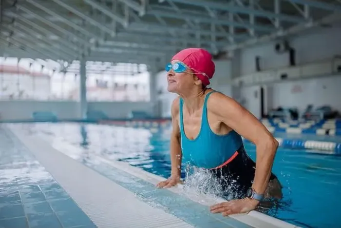Framed Print : Happy senior woman getting out of the swimming pool indoors Framed Print : Happy senior woman getting out of the swimming pool indoors