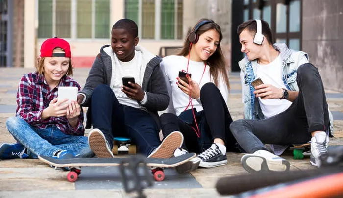 Framed Print : Happy teens playing on smarthphones and listening to music
