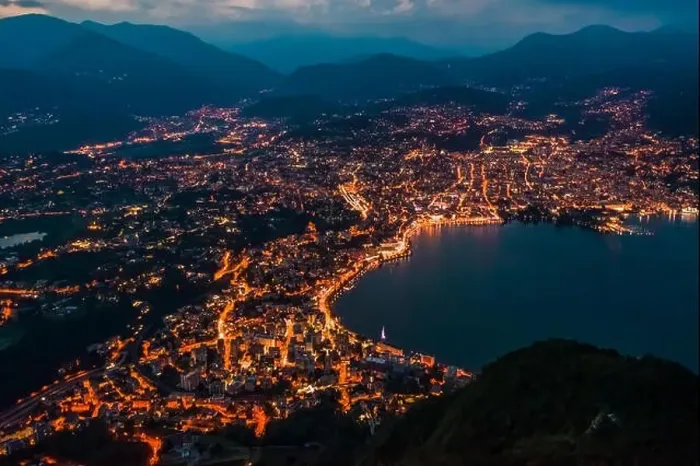 Framed Print : High angle aerial drone night shot of city street lights by lake in Lugano, Switzerland Framed Print : High angle aerial drone night shot of city street lights by lake in Lugano, Switzerland
