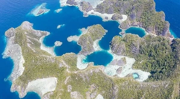 Highly eroded limestone islands rise from the beautiful, tropical seascape in Raja Ampat, Indonesia. This remote region is known for its biodiversity
