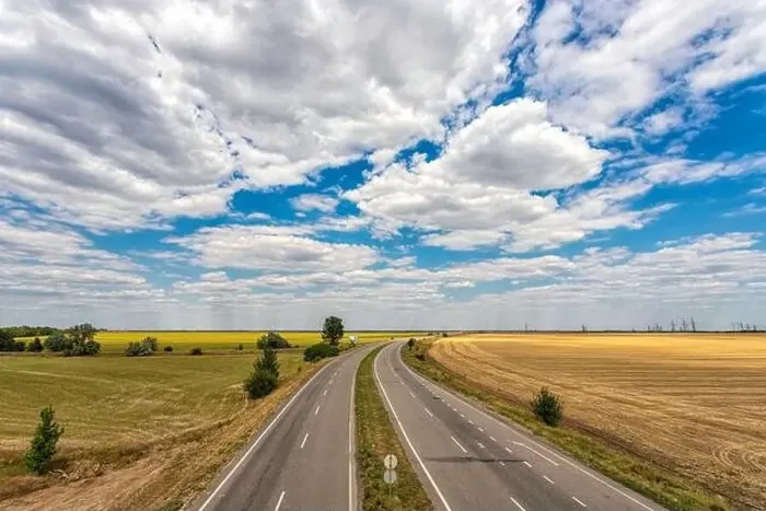 Framed Print : highway passing through the fields against a blue sky with beautiful white clouds Framed Print : highway passing through the fields against a blue sky with beautiful white clouds