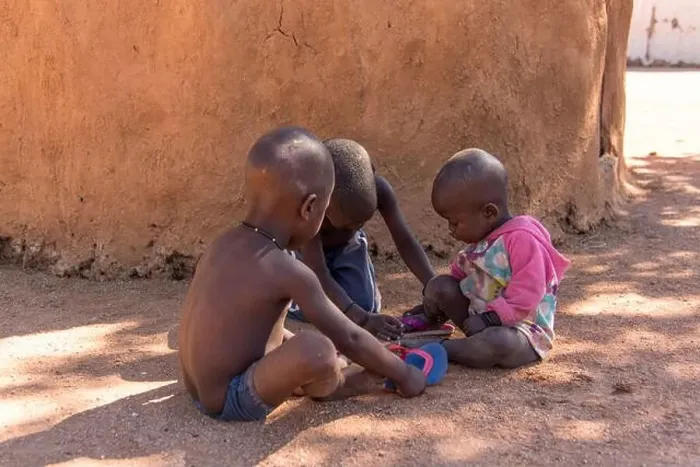 Framed Print : Three Himba children play in the shade of a mud hut Framed Print : Three Himba children play in the shade of a mud hut