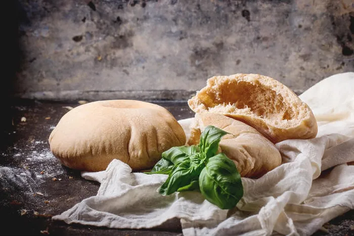 Framed Print : Two homemade whole and sliced pita bread stuffed with fresh basil on white textile, served with flour over dark table Framed Print : Two homemade whole and sliced pita bread stuffed with fresh basil on white textile, served with flour over dark table
