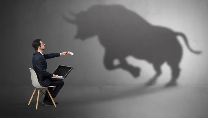 Framed Print : Humble businessman staying and offering stuffs to a huge angry bull shadow