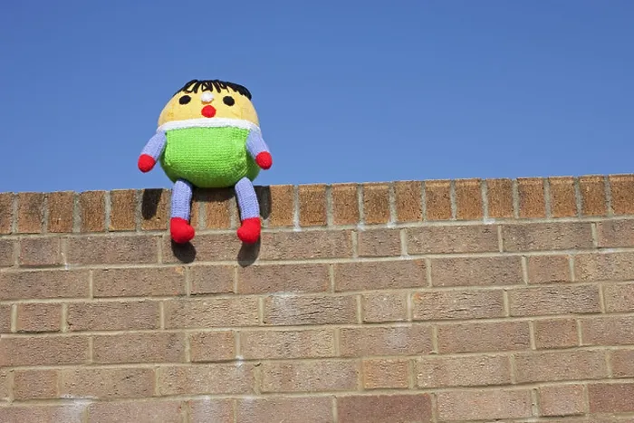 Framed Print : A Humpty Dumpty soft toy sat on the wall with a blue sky background Framed Print : A Humpty Dumpty soft toy sat on the wall with a blue sky background
