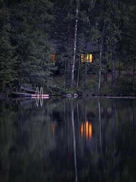 Idyllic cottage view with cozy cottage and window ligth at tranquil summer night in Finland