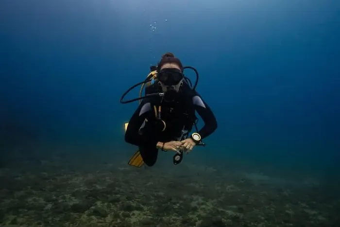 Framed Print : In this image, a female diver is depicted swimming underwater in a clear blue ocean environment Framed Print : In this image, a female diver is depicted swimming underwater in a clear blue ocean environment