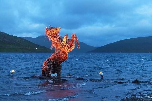 Incredible evening scene with luminous mythical horse Nykur Nix Statue in Sorvagsvatn lake waters near the airport in Vagar on the Faroe Islands
