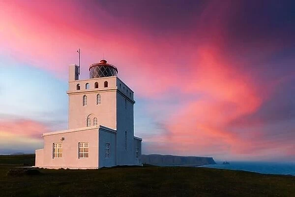 Incredible evening view of Dyrholaey Lighthouse at Cape Dyrholaey, south coast of Iceland. Great purple sunset glowing on background