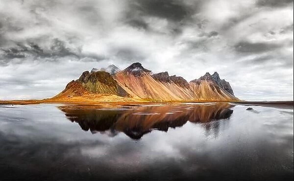 Incredible landscape of the famous Stokksnes mountains on Vestrahorn cape. Reflection in the clear water on the epic skies background, Iceland