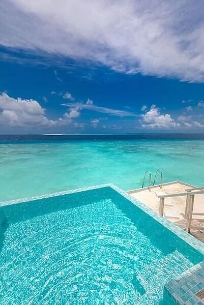 Infinity swimming pool with sea and ocean view on blue sky background. Luxury infinity pool over amazing turquoise lagoon and ladder into the water