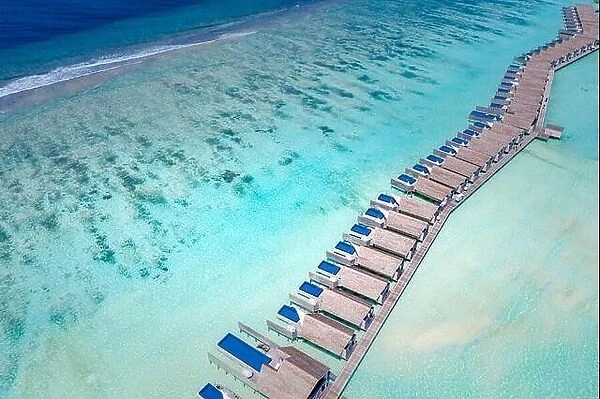 Island resort in Indian ocean, Maldives. Luxury over water villas bungalow with sandbank and amazing lagoon close to ocean reef
