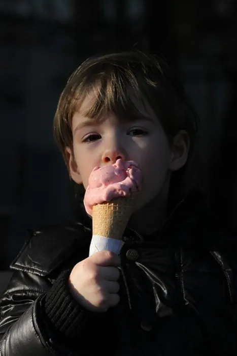 Framed Print : An Italian girl enjoys the first days of spring licking an ice cream cone outside. Spilimbergo, Italy