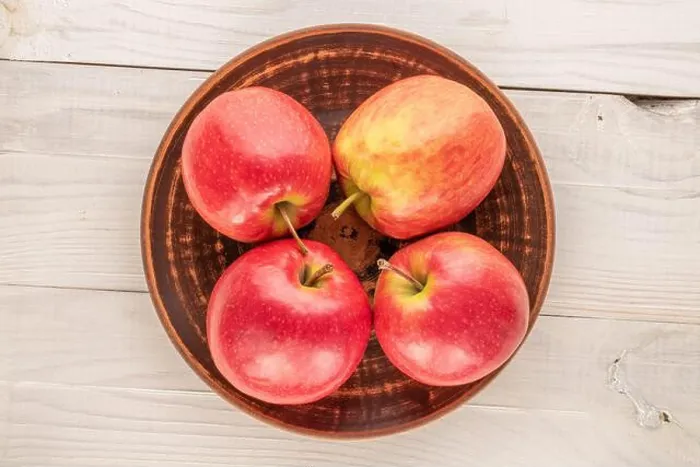 Framed Print : Four juicy red apples with a ceramic plate on a wooden table, close-up, top view Framed Print : Four juicy red apples with a ceramic plate on a wooden table, close-up, top view
