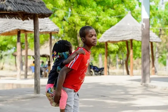 Framed Print : KOUTAMMAKOU, TOGO - JAN 13, 2017: Unidentified Togolese boy in red shirt carries his little sister in the village Framed Print : KOUTAMMAKOU, TOGO - JAN 13, 2017: Unidentified Togolese boy in red shirt carries his little sister in the village