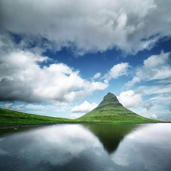 Landscape with Kirkjufell mountain, clear lake and cloudscape in blue sky