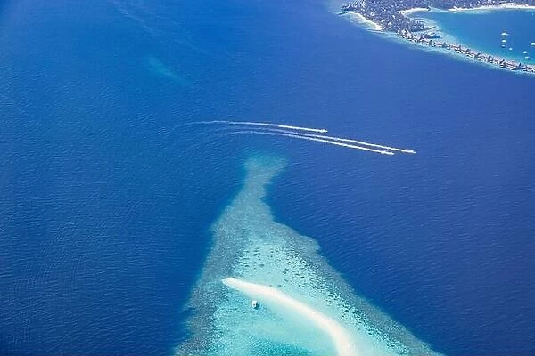 Landscape seascape aerial view over Maldives luxury resort villas with atoll sandbank island. Jet skis having fun in ocean lagoon. Luxurious summer