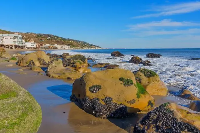 Framed Print : Large rocky shoreline of Malibu Beach featuring homes in the background against a clear sky Framed Print : Large rocky shoreline of Malibu Beach featuring homes in the background against a clear sky