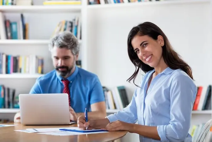 Framed Print : Laughing mexican businesswoman with colleague at desk at office of start up company Framed Print : Laughing mexican businesswoman with colleague at desk at office of start up company