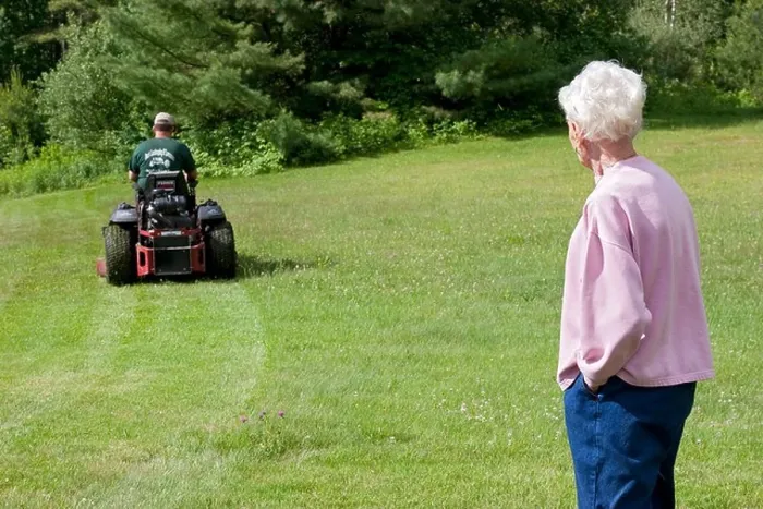 Framed Print : Lawn care service mowing elderly woman's lawn while she watches Framed Print : Lawn care service mowing elderly woman's lawn while she watches