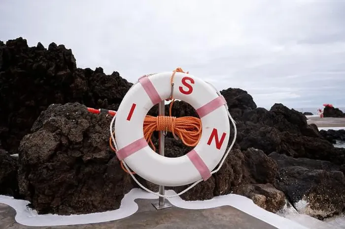Framed Print : A lifebuoy with orange rope stands ready against dark volcanic rocks at Porto Moniz natural pools Framed Print : A lifebuoy with orange rope stands ready against dark volcanic rocks at Porto Moniz natural pools