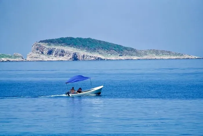 Framed Print : Little boat on the ocean in front of an island Framed Print : Little boat on the ocean in front of an island