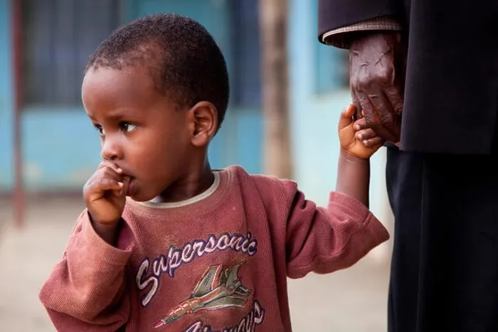 Framed Print : little boy at an old man's hand is sucking on his thumb, Burundi, Bujumbura Marie, Bujumbura