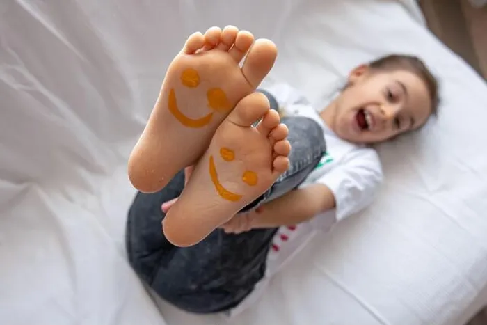 Framed Print : A little girl is lying on a sofa with her feet painted with paints. Funny smiles on children's feet Framed Print : A little girl is lying on a sofa with her feet painted with paints. Funny smiles on children's feet