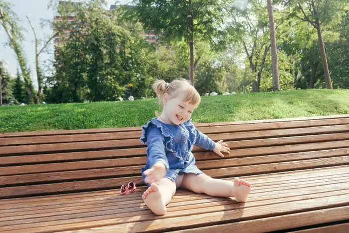 Framed Print : Little girl sitting on the bench and laughing in a city park on a warm sunny day Framed Print : Little girl sitting on the bench and laughing in a city park on a warm sunny day