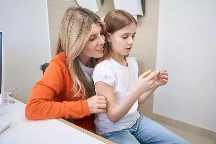 Framed Print : Little girl sitting on mother's knee in doctor office and looking at thermometer Framed Print : Little girl sitting on mother's knee in doctor office and looking at thermometer