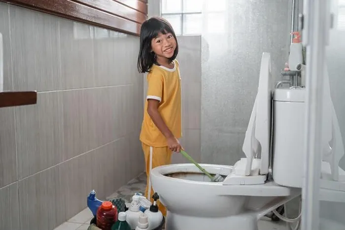 Framed Print : The little girl smiles at the camera while using the toilet brush to clean the dirty toilet Framed Print : The little girl smiles at the camera while using the toilet brush to clean the dirty toilet