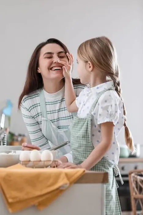 Framed Print : Little girl touching her mother's nose while cooking in kitchen on Easter day Framed Print : Little girl touching her mother's nose while cooking in kitchen on Easter day