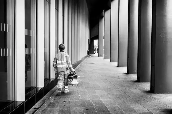 Framed Print : London black and white street photography: Workman carrying Numatic Henry vacuum cleaner in street