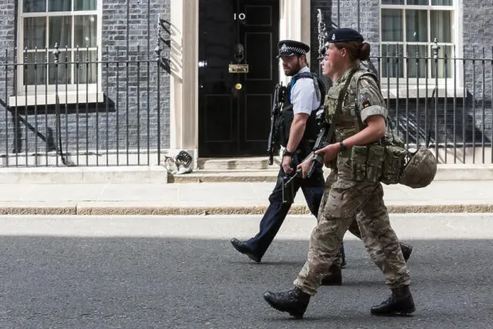Framed Print : London, UK. 24 May 2017. A police officer and two female soldiers walk past the front door of No Framed Print : London, UK. 24 May 2017. A police officer and two female soldiers walk past the front door of No