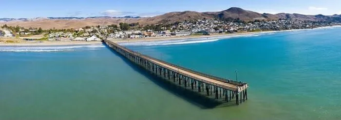 Framed Print : A long pier reaches out into the Pacific Coast in the quaint city of Cayucos, California. This California region is known for its coastal scenery Framed Print : A long pier reaches out into the Pacific Coast in the quaint city of Cayucos, California. This California region is known for its coastal scenery