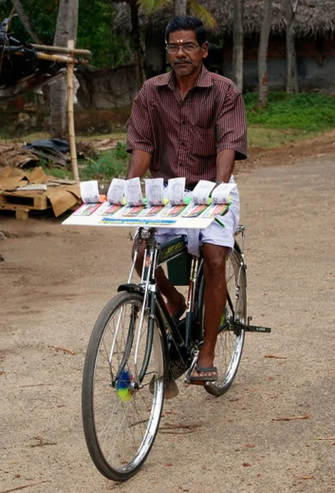 Framed Print : Lottery ticket seller riding bicycle scene from Kerala Framed Print : Lottery ticket seller riding bicycle scene from Kerala