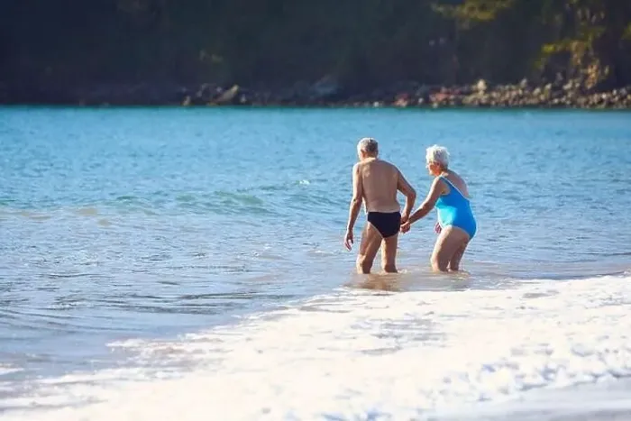 Framed Print : Loving Senior Couple Holding Hands As They Walk Into Sea For Swim Framed Print : Loving Senior Couple Holding Hands As They Walk Into Sea For Swim