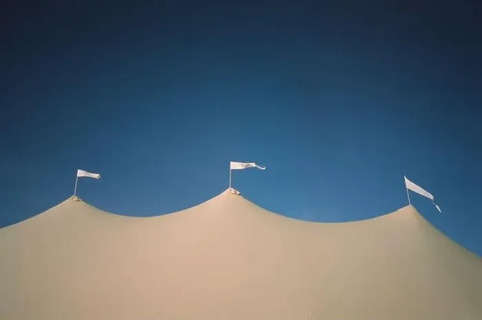 Framed Print : A low angle shot of three white flags waving in the wind on top of a medieval-style tent under a blue sky Framed Print : A low angle shot of three white flags waving in the wind on top of a medieval-style tent under a blue sky