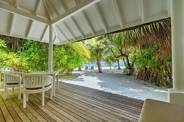 Luxury beach villa, backyard deck with chairs and table. Relaxing beach scene, palm trees, white sand and sea view