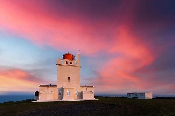 Magic evening view of Dyrholaey Lighthouse at Cape Dyrholaey, south coast of Iceland. Great purple sunset glowing on background. Landscape photography