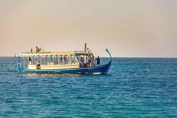 Maldives: Wonderful Maldivian boat Dhoni on tropical blue sea, taking tourist to a sunset cruise