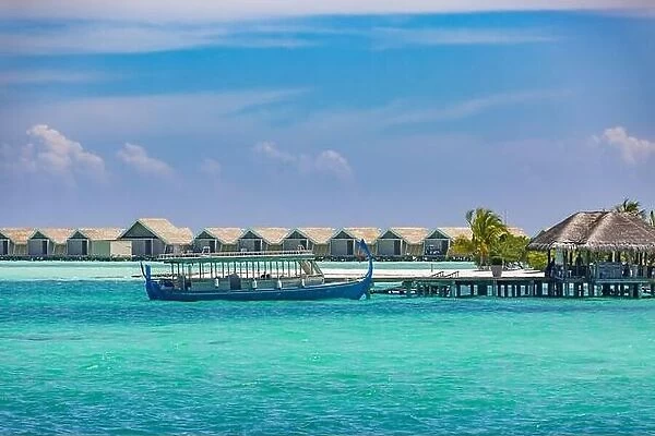 Maldivian water bungalows. Luxury travel background, exotic over water villas, wooden boat Dhoni. Summer travel destination