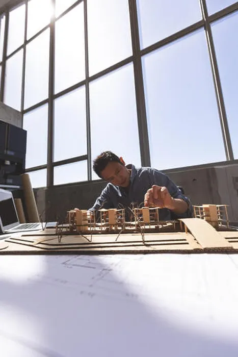 Framed Print : Male architect working on architectural model at desk in a modern office Framed Print : Male architect working on architectural model at desk in a modern office