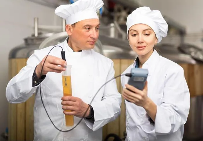 Framed Print : Male and female brewers measuring pH in beer with digital meter Framed Print : Male and female brewers measuring pH in beer with digital meter