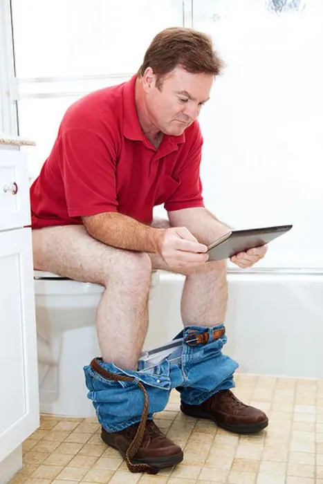 Framed Print : Man reading a tablet pc while using the toilet in the bathroom Framed Print : Man reading a tablet pc while using the toilet in the bathroom