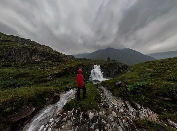 Framed Print : man in red stands under waterfall on black rock in mountains on cloudy rainy day.. Wide panorama Framed Print : man in red stands under waterfall on black rock in mountains on cloudy rainy day.. Wide panorama
