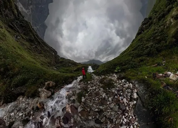 Framed Print : man in red stands under waterfall on black rock in mountains on cloudy rainy day.. Wide panorama