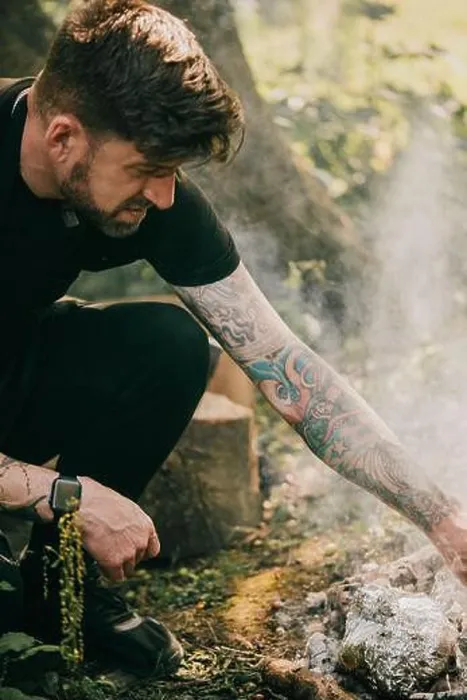 Framed Print : A man with tattoos on his arm is sitting on the ground next to a fire Framed Print : A man with tattoos on his arm is sitting on the ground next to a fire